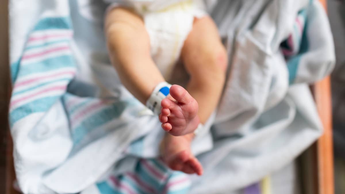 Närbild av en nyfödds fötter. Den nyfödda ligger i en sjukhussäng.