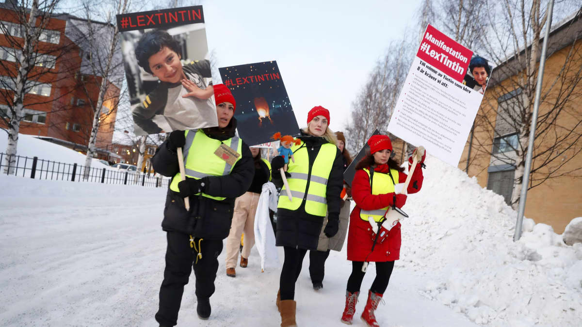 Mielenosoittajat kantavat kylttejä ja kävelevät lumisessa maisemassa.
