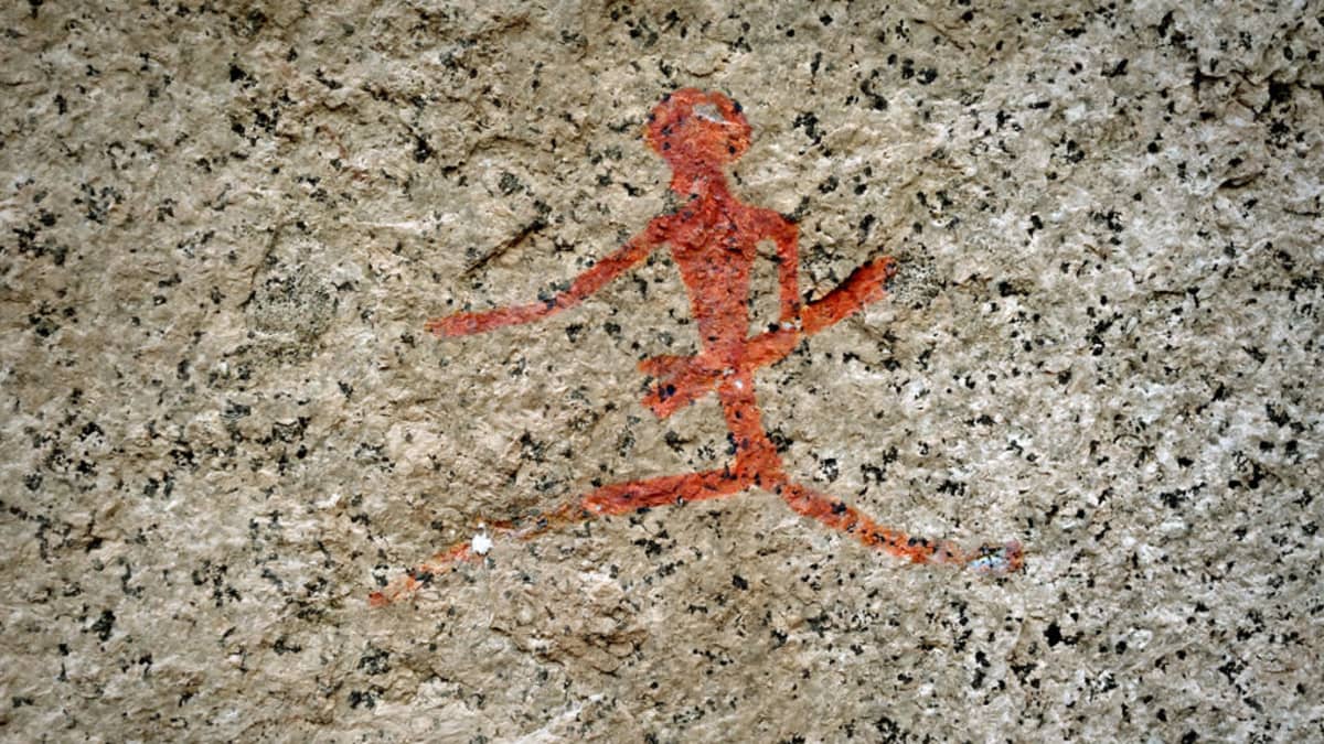 Kallioon punavärillä maalatttu juokseva ihmishahmo pitkänomainen ase kädessä.