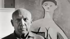 Pablo Picasso maalauksensa edessä.