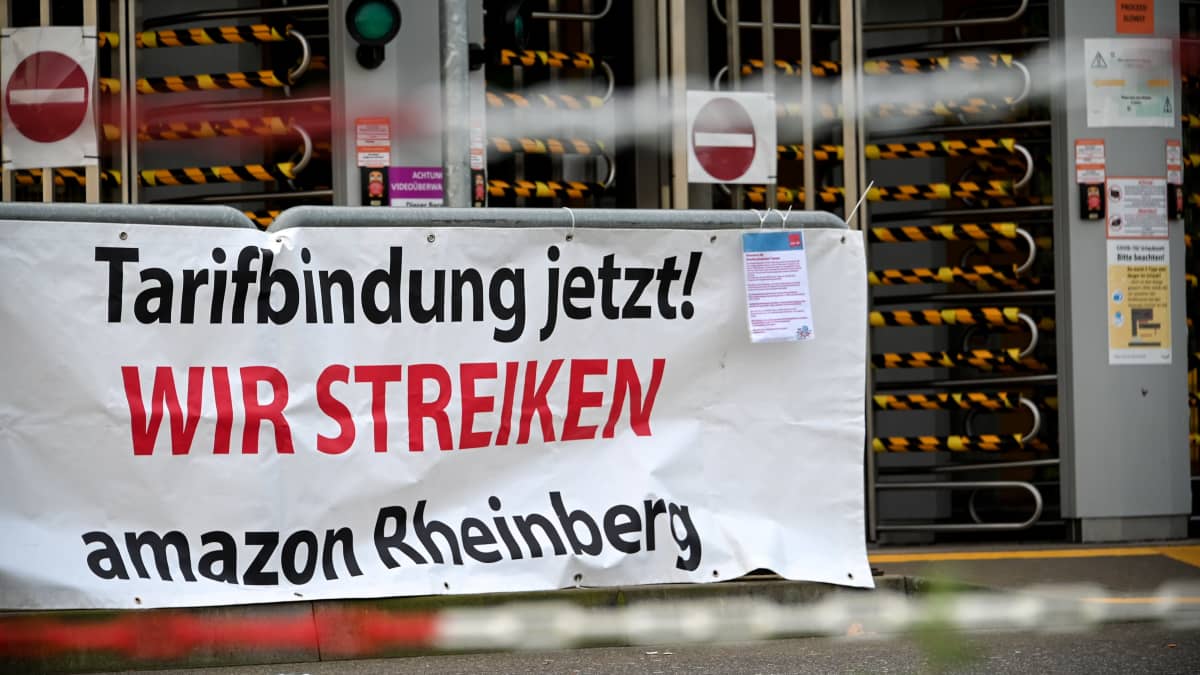 Verdi-ammattiliiton esille panema mielenosoitusjuliste Amazonin jakelukeskuksessa Rheinbergissä, Saksassa. Julisteessa vaaditaan kollektiivista neuvotteluoikeutta.
