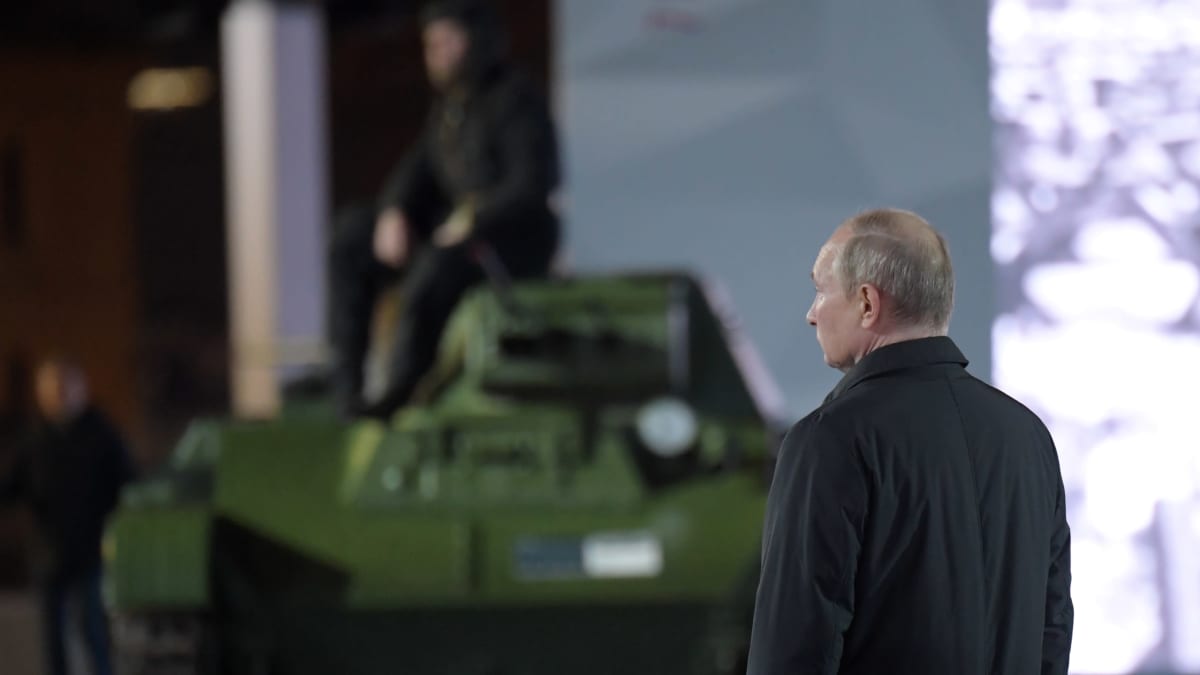 Vladimir Putin seisoo. Taustalla panssarivaunu.