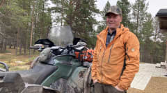 Osmo Seurujärvi seisoo mönkijän vieressä ja katsoo kameraan ja hymyilee.