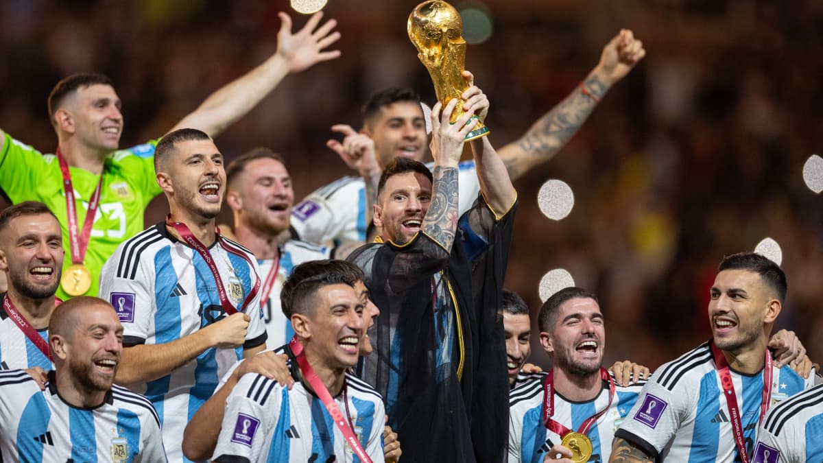 Lionel Messi nostaa MM-pokaalia joukkuekavereidensa keskellä.