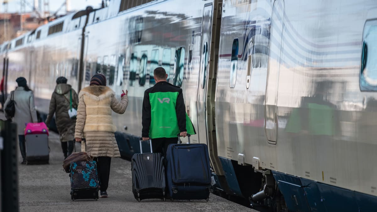 Viimeinen Allegro-juna lähti Pietariin Helsingin rautatieasemalta. VR:n työntekijä auttaa matkustajaa matkatavaroiden kanssa.