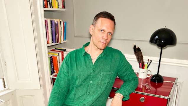 Designstjärnan Teemu Suviala i grön skjorta sitter vid sitt skrivbord.