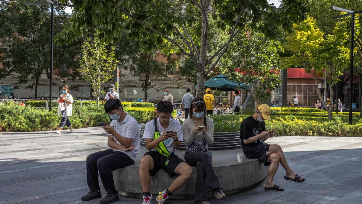 Nuoret puhelimiensa äärellä Kiinan pääkaupungissa Pekingissä Sanlitunin kaupunginosassa. Jatkossa nettipelaamiseen tulee tuntuva leikkaus: vain kolme tuntia viikossa.