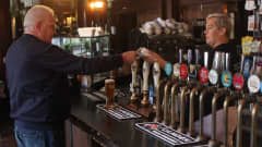 Asiakas maksaa luottokortilla oluen lontoolaisessa pubissa. 