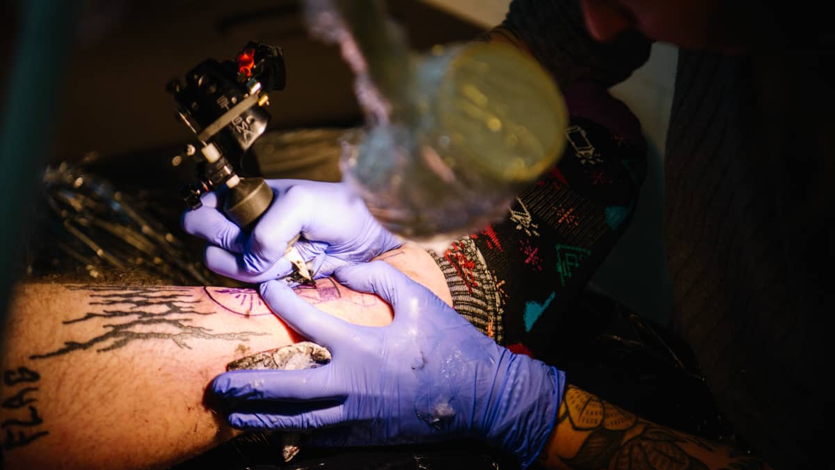 Tatuointia tehdään henkilön sääreen.