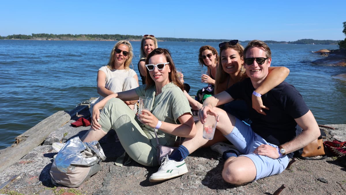 Ryhmä hollantilaisturisteja viettämässä juhannusta Lonnan saarella. Kuuden hengen porukka poseeraa kameralle kivillä istuen. 