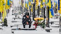 Mies istuu haudan äärellä lumisella hautausmaalla. Hautojen päätyihin on kiinnitetty Ukrainan lippuja.