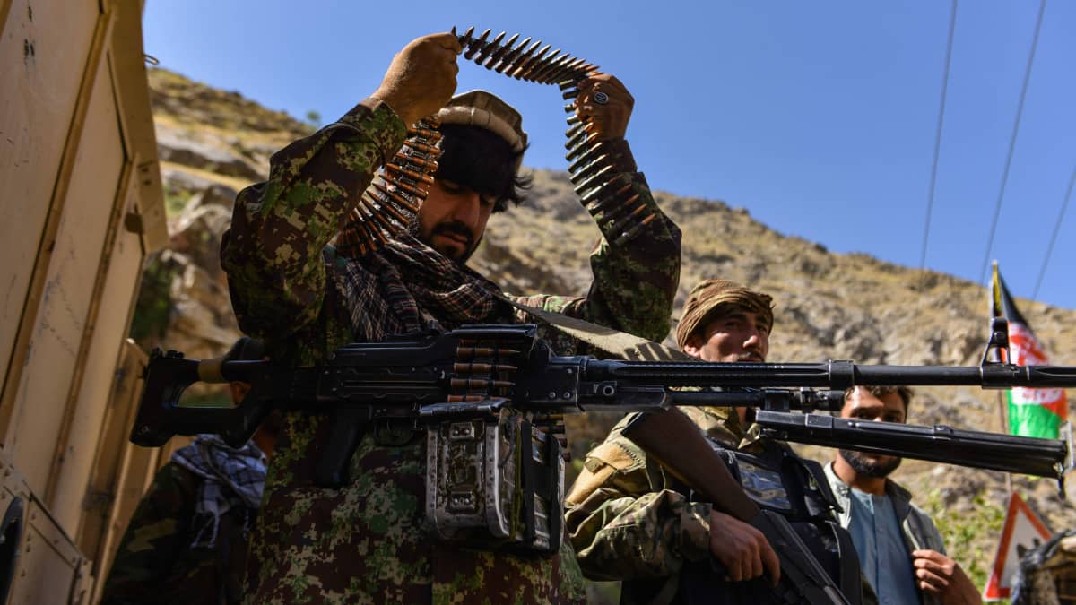 Anti-Taliban vastarintataistelija riisuu konekiväärin ammuksia hartioilta.