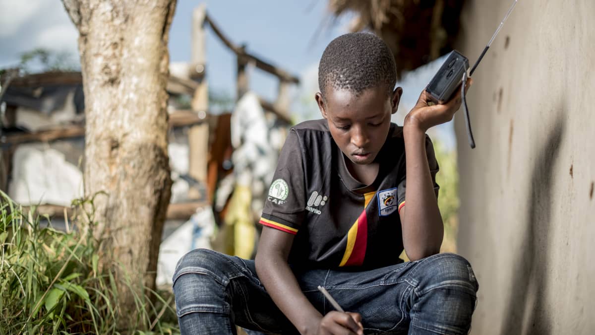ugandalainen poika opiskelee radion välityksellä