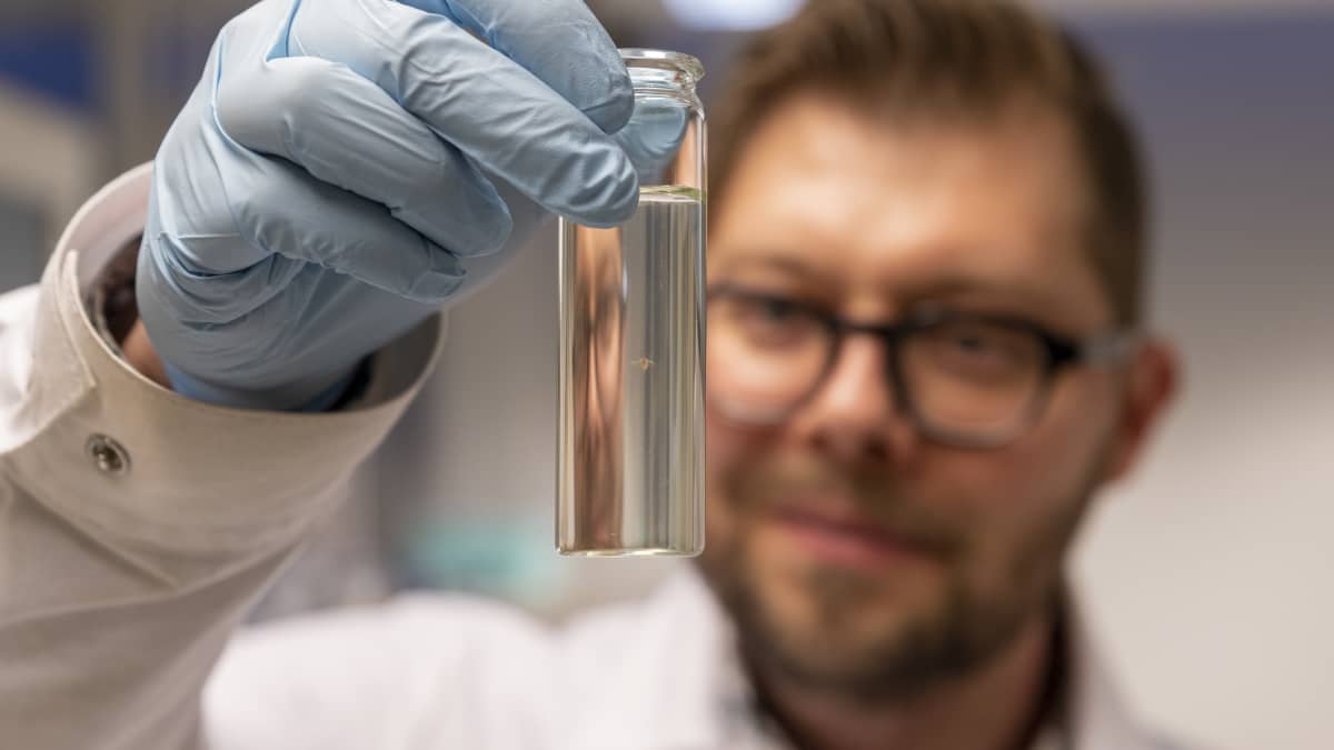 Tutkija Sami Taipale pitelee laboratoriossa käsissään pientä lasipulloa, jossa uiskentelee tutkimuksessa käytetty vesikirppu.