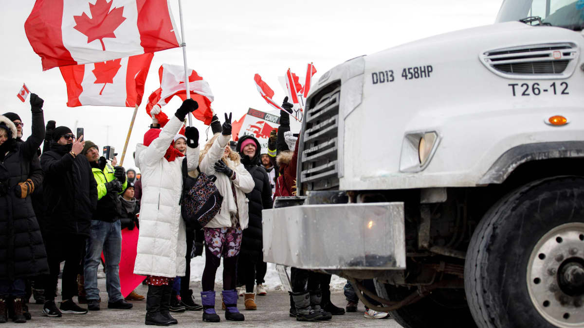 Mielenosoittajat heiluttelevat Kanadan lippua rekan vieressä.
