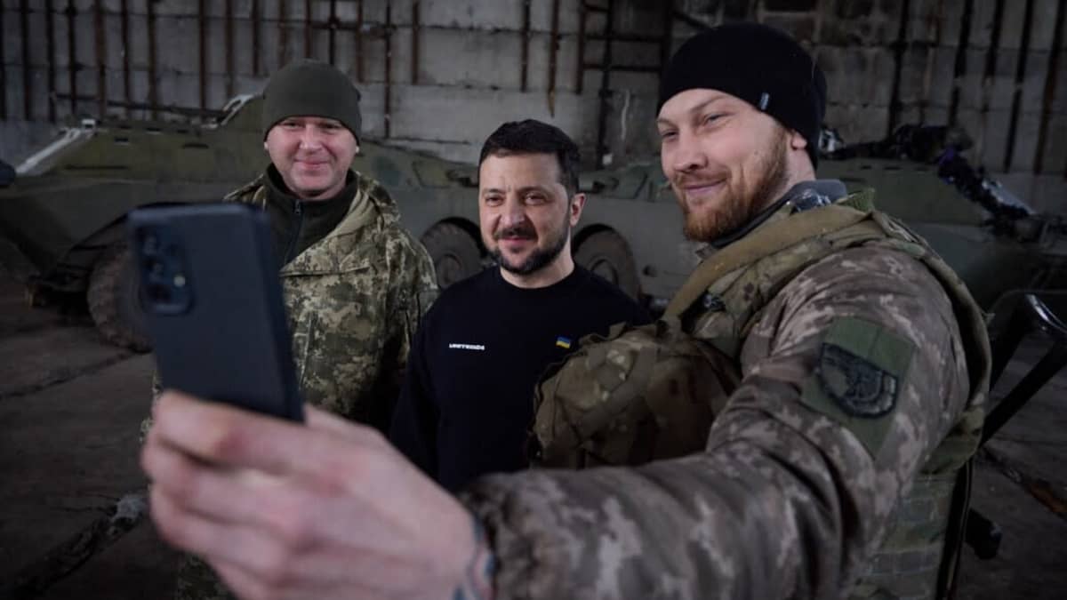 Hymyilevä sotilas ottaa selfietä Ukrainan presidentin Volodymyr Zelenskyin kanssa.