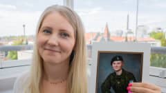 Iida-Amalia Nikkilä pitää kädessä valokuvaa inttiajalta.