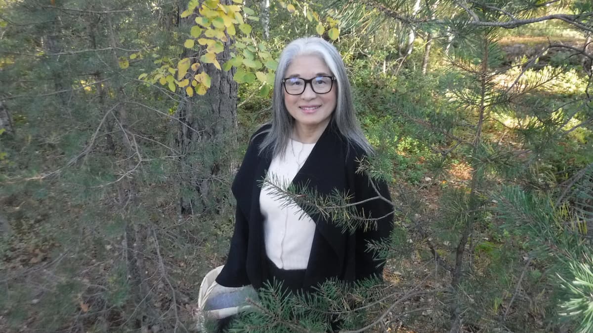 Naomi Moriyama seisoo syksyisessä metsässä kori kädessään