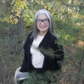 Naomi Moriyama seisoo syksyisessä metsässä kori kädessään
