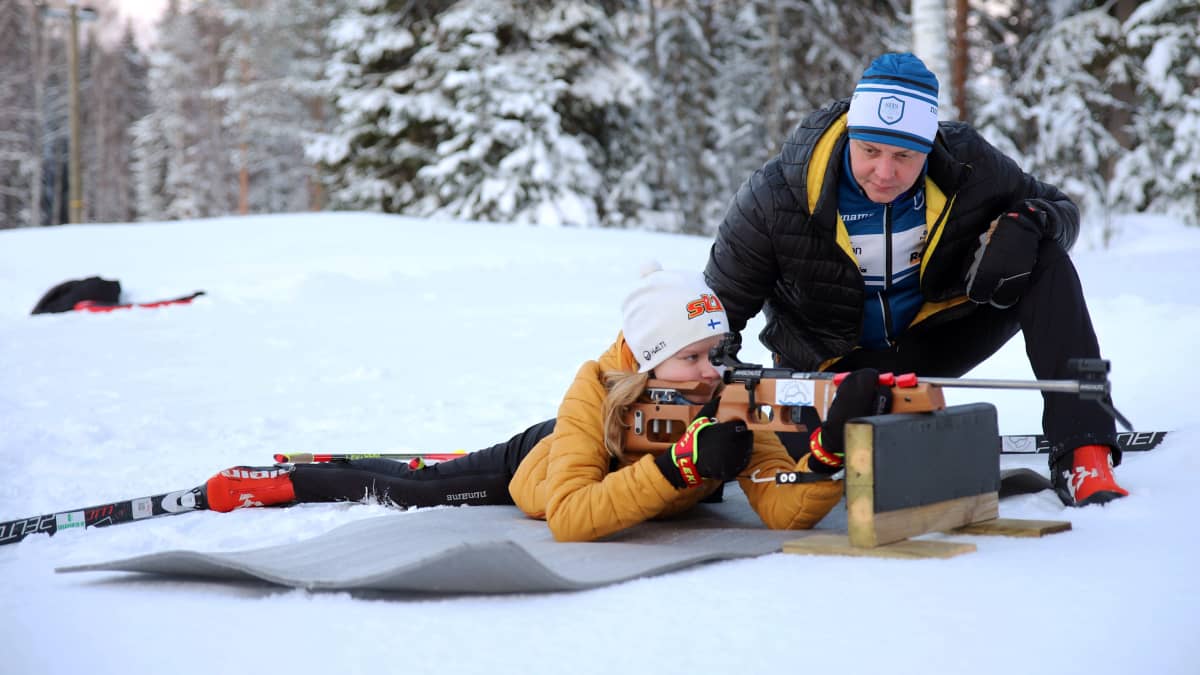 Ampumahiihtoa harrastava Anni Saksman harjoittelee ampuma-asentoa isänsä kanssa Savonlinnan Aholahdessa.