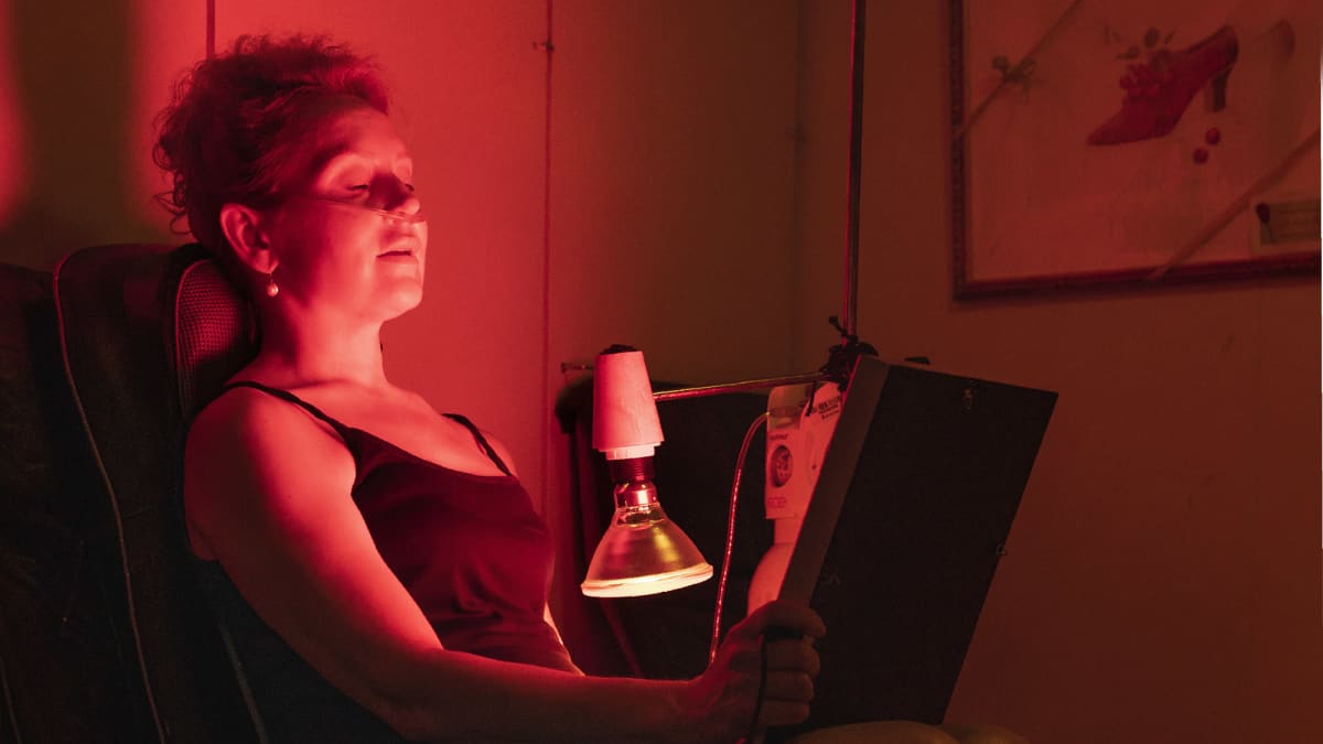 Marie Finne-Bray istuu infrapunavalossa kasvoillaan happiviikset.