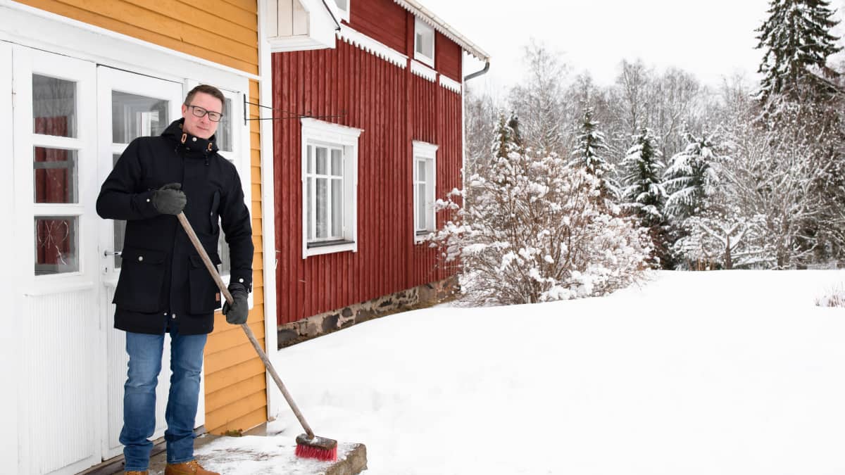 Janne Tyynismaa lakaisee talon portaita talvipäivänä.