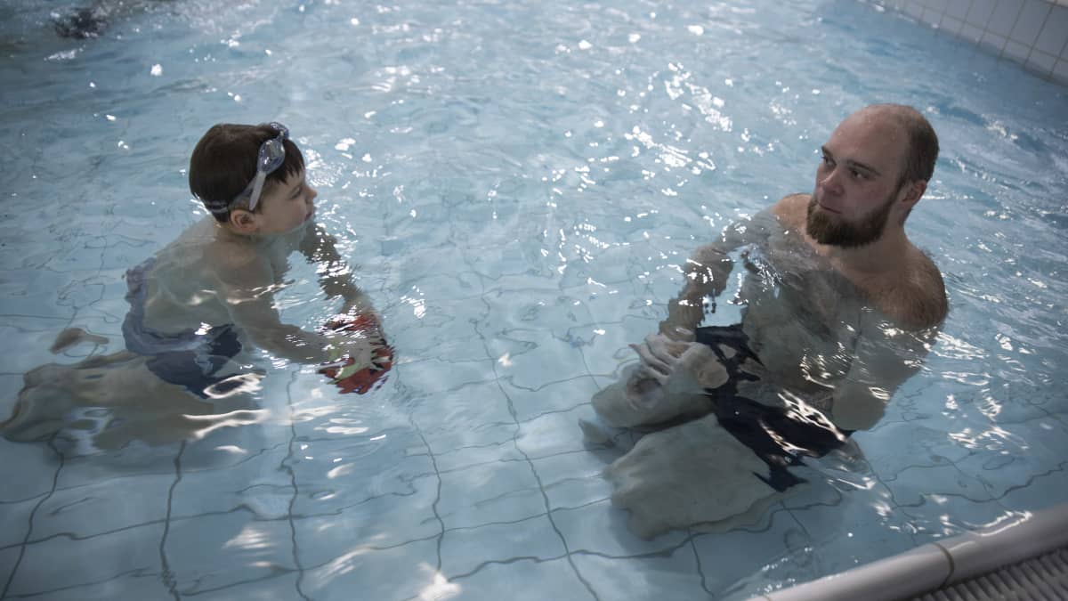 Isä ja poika uimassa lasten altaassa.