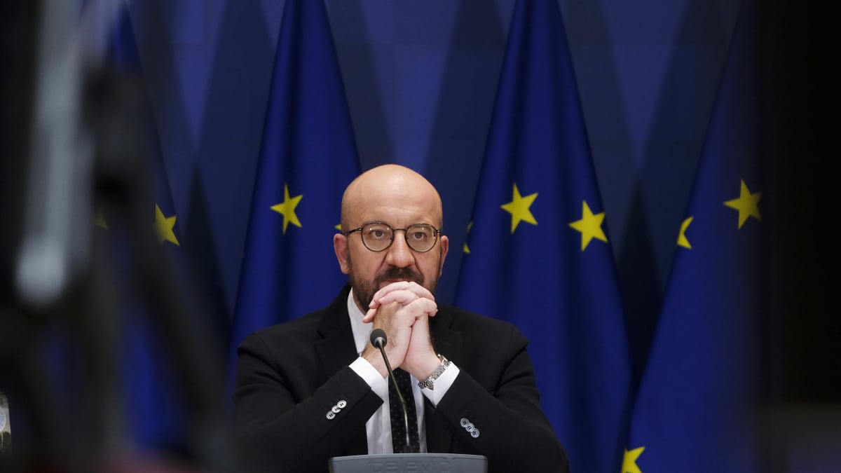 Europeiska rådets ordförande Charles Michel sitter med händerna knäppta framför hakan. I bakgrunden flera EU-flaggor.