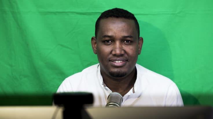 Hassan Halanen juontamassa podcast lähetystä omassa olohuoneessaan.