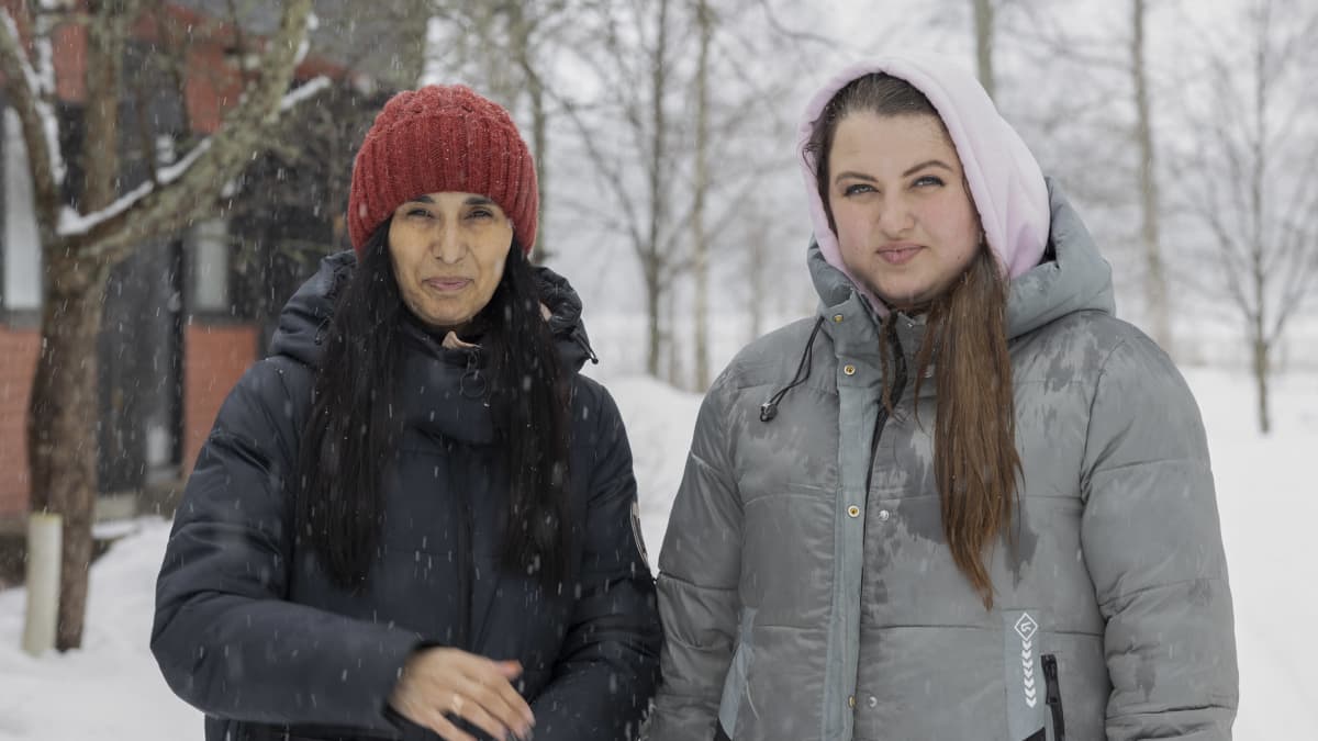 Marina Korisna ja Tatjana Makushenko seisovat lumisateessa Salmirannan vastaanottokeskuksen asuntojen edustalla. 