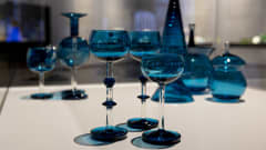 Nanny Stillin suunnittelemia sinisä Harlekiini-sarjan lasiesineitä. Etualalla kolme jalallista lasia.