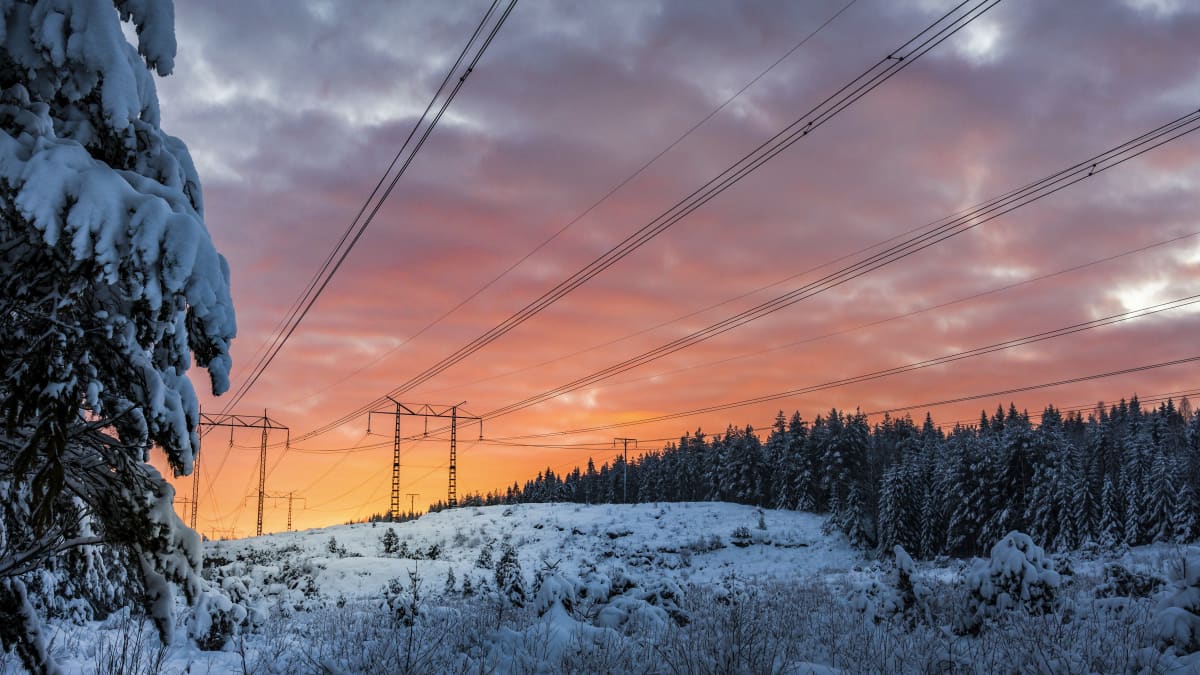 Elkablar och elverk i ett vintrigt landskap i solnedgång.