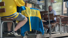 Ravintolan terassipöydälle on levitetty Ruotsin lippu. Pöydän ääressä istuu sinikeltaisiin vaatteisiin pukeutunut henkilö.