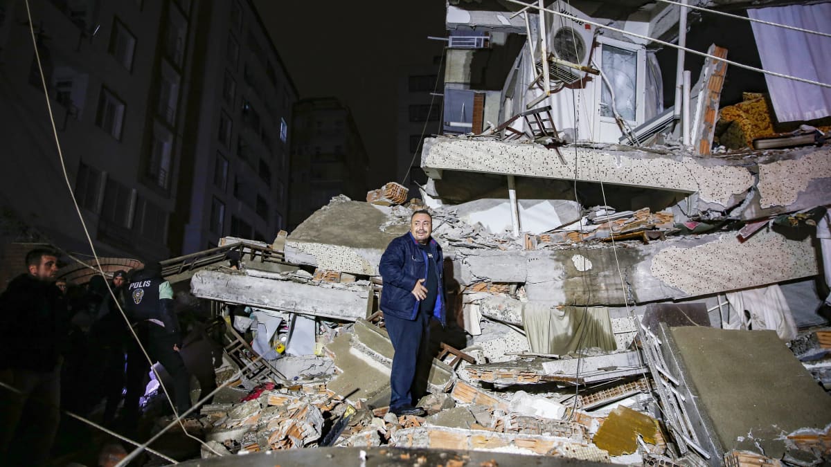 Henkilö seisoo romahtaneen rakennuksen raunioissa.
