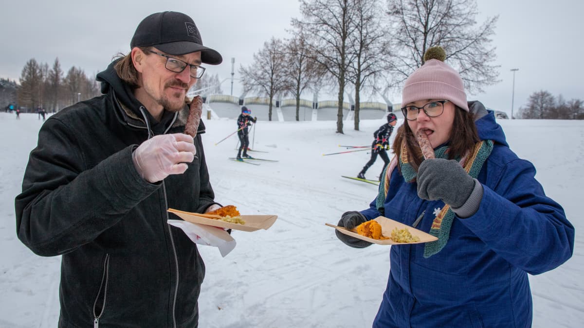 Aleksi Kärkkäinen ja Mari Karjalainen maistavat lihavartaita hiihtoladun varressa.