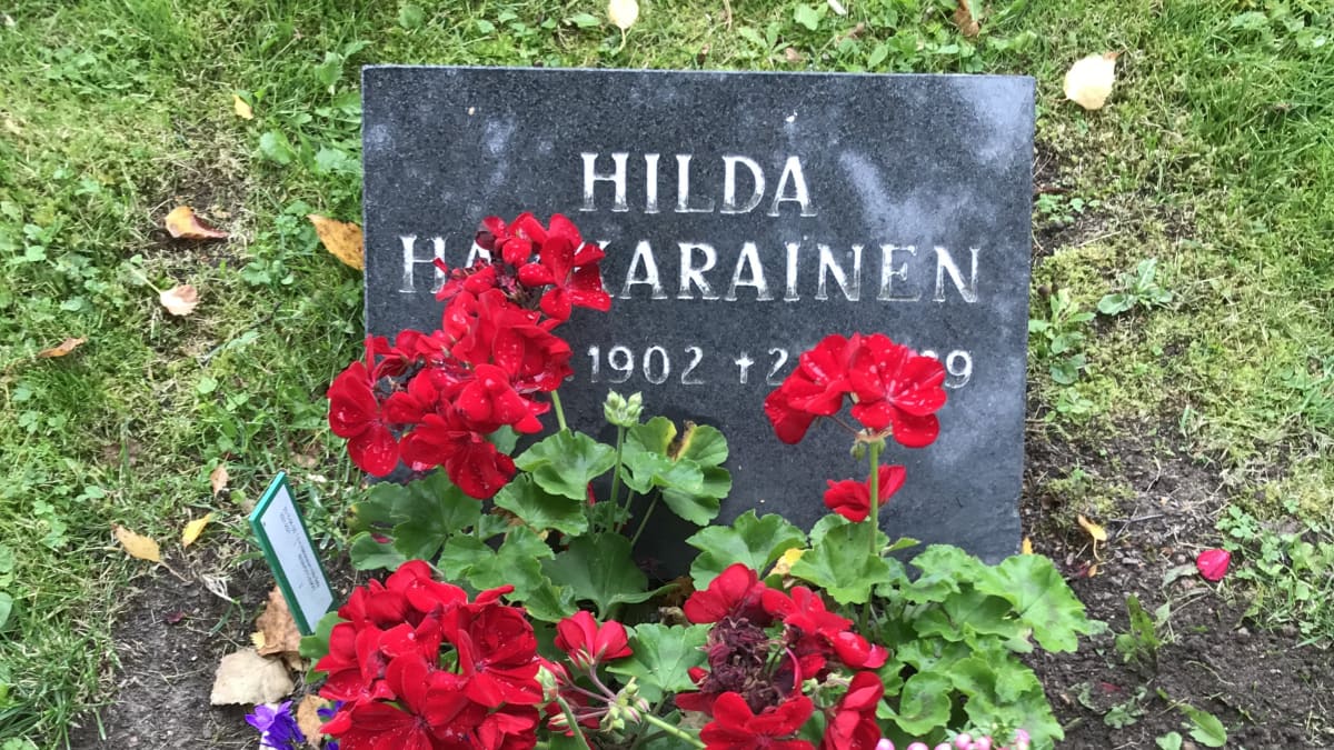Hautakivi, jossa lukee Hilda Hakkarainen. Kukkia haudalla.