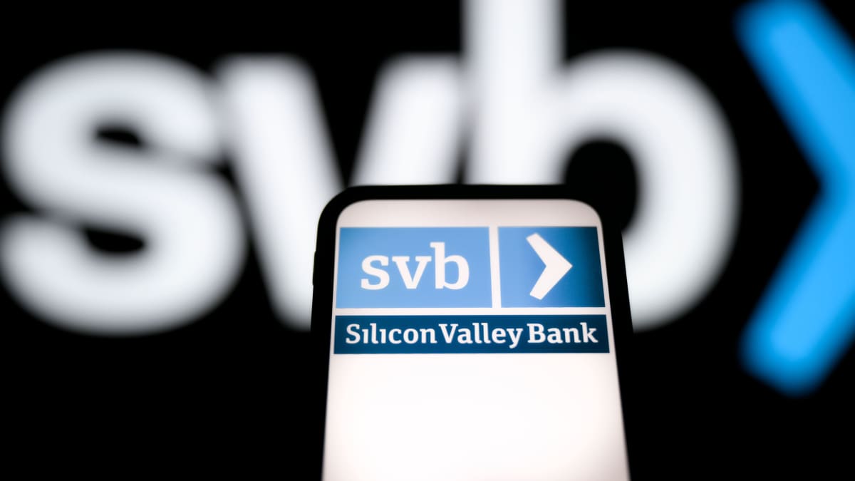 Matkapuhelimen näyttö, jossa lukee Silicon Valley Bank ja SVB. Myös mustalla taustalla näkyy SVB:n sinivalkoinen logo.