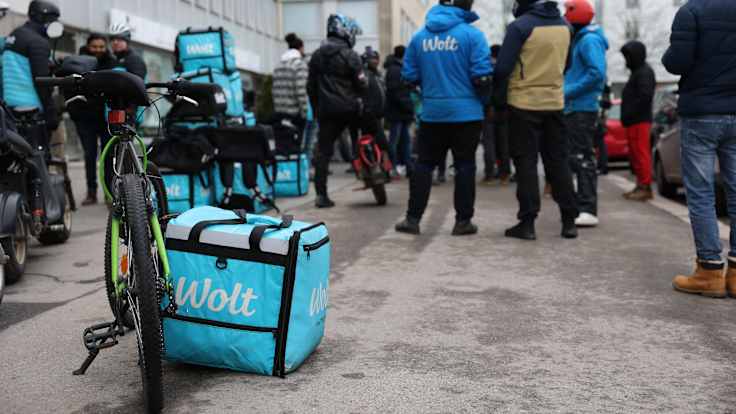 A courier backpack and bicycle in the foreground, with a number of people wearing cold weather clothes protest in the background.
