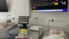 Kaksi nukkea potilassängyissä makaamassa, seinällä monitoreja. Hoitotyön luokka.
