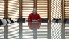 Elintarvikemarkkinavaltuutettu Olli Wikberg istuu tyhjän neuvottelupöydän ääressä ja katsoo suoraan kameraan.