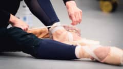 Tanssija Maria Baranova sitoo balettitossun nauhoja.