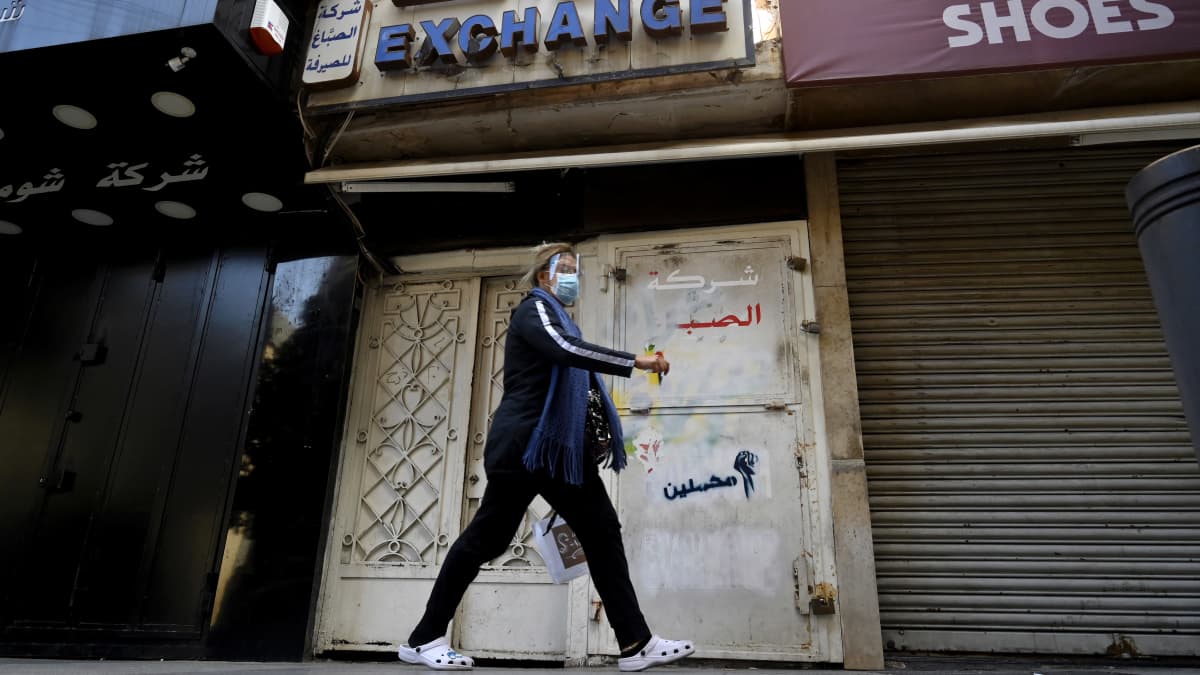 Nainen kävelee kiinni olevan valuutanvaihdon ohitse Beirutissa.   A woman walks in front of a closed currency exchange shop at Hamra street in Beirut, Lebanon, 17 March 2021.
