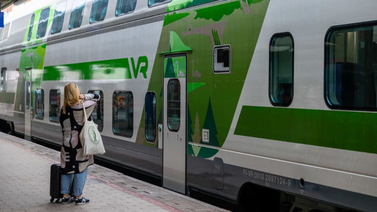 Matkustaja laukkuineen junan vaunun vieressä Tampereen rautatieasemalla.
