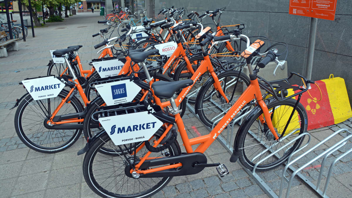 Orangea cyklar i en cykelställning.
