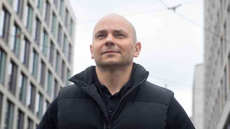 Andrei Pivovarov katsoo kamerasta ohi kauas kaukaisuuteen. Takana valkoinen taivas ja kerrostaloja.