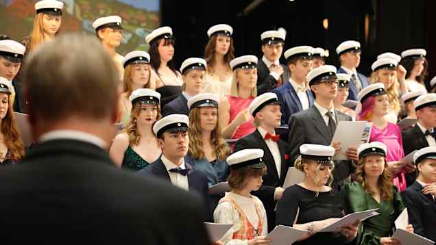 Ylioppilaat laulavat lakit päässä.