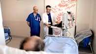 Lääkäri ja sairaanhoitaja seisovat huoneessa näyttöpäätteen edessä, etualalla näkyy potilaan pää.
