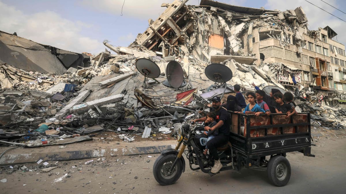 Palestiinalaiset siviilit moottoriajoneuvon kyydissä raunioituneella kadulla. 