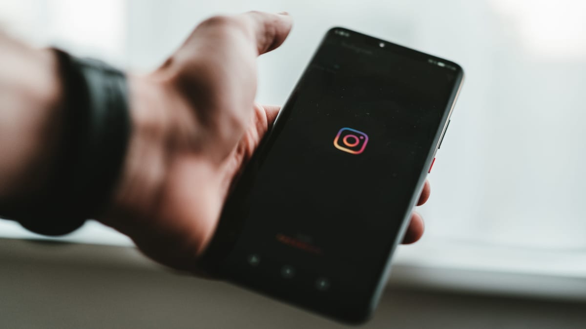 En person håller i en mobil där Instagram-appen öppnas.