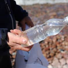 Jouni Kelkka pitelemässä Lehmäsaaren rannalta löytynyttä muovipulloa Kotkassa.